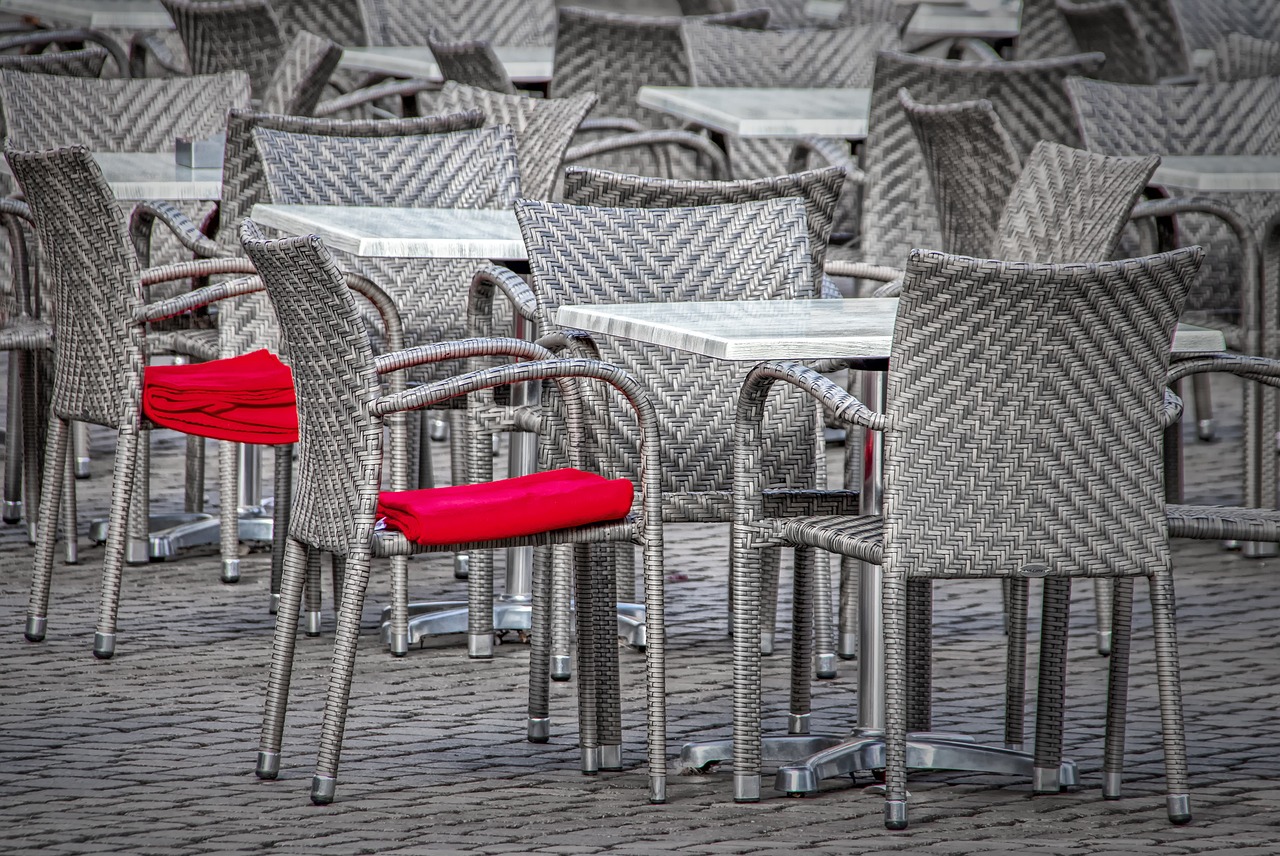 a group of chairs and tables, two chairs with red blankets folded on top