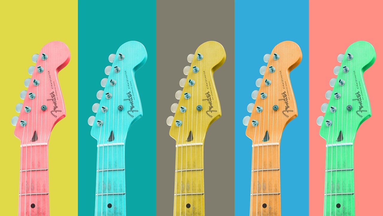 head and necks of five guitars, each in a different colour